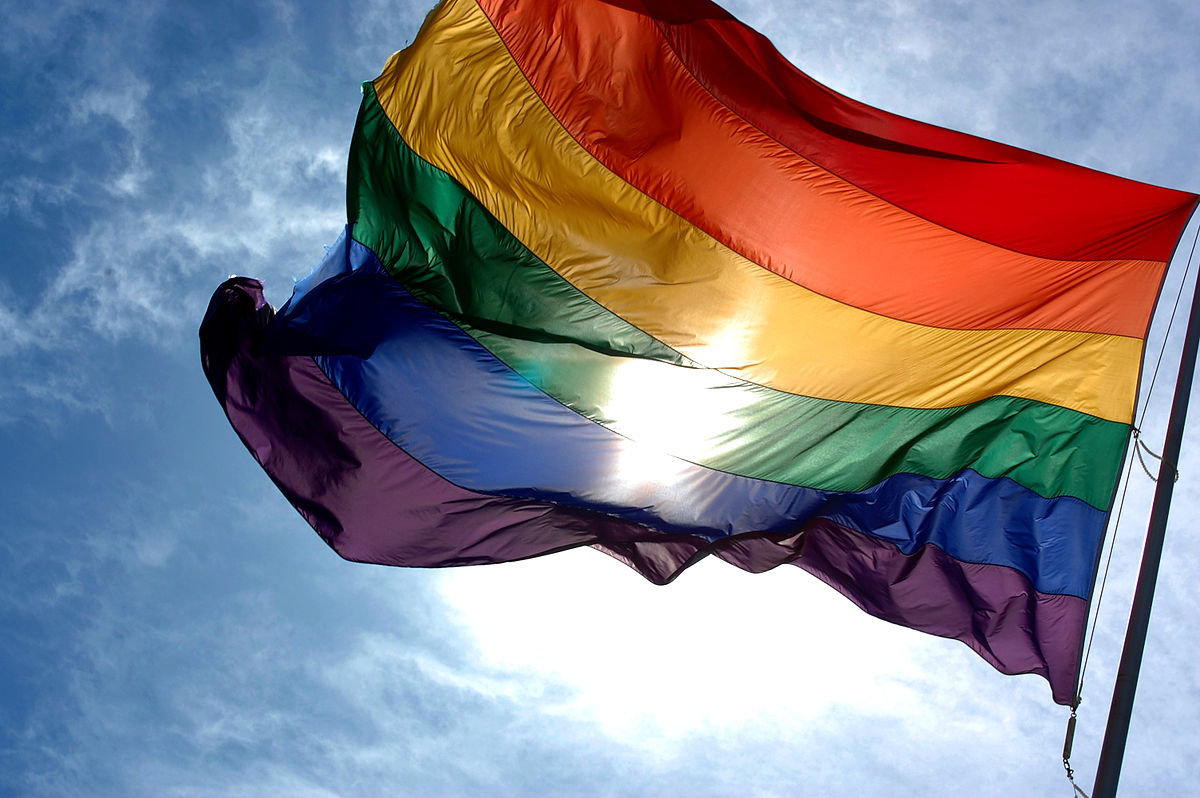 1200px-Rainbow_flag_and_blue_skies