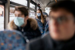 Young girl sitting on a bus with a face covering on.
