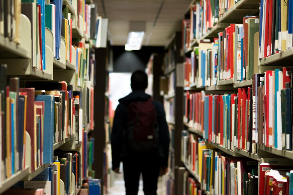 Teenage boy walking in the library, photographed from behind