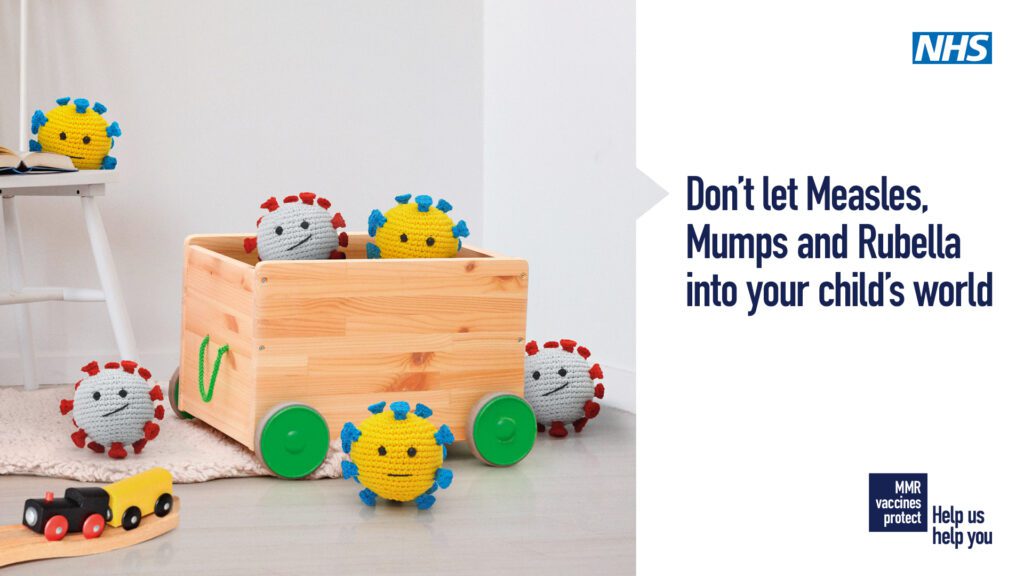 Photograph of a child's toy box with toys surrounding it. Wording to the left reads 'Don't let measles, mumps and rubella into your child's world'