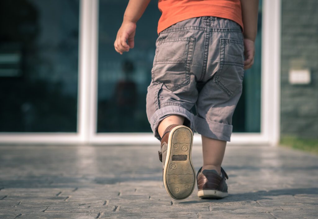 Image of a child walking, with their shoes and legs on display