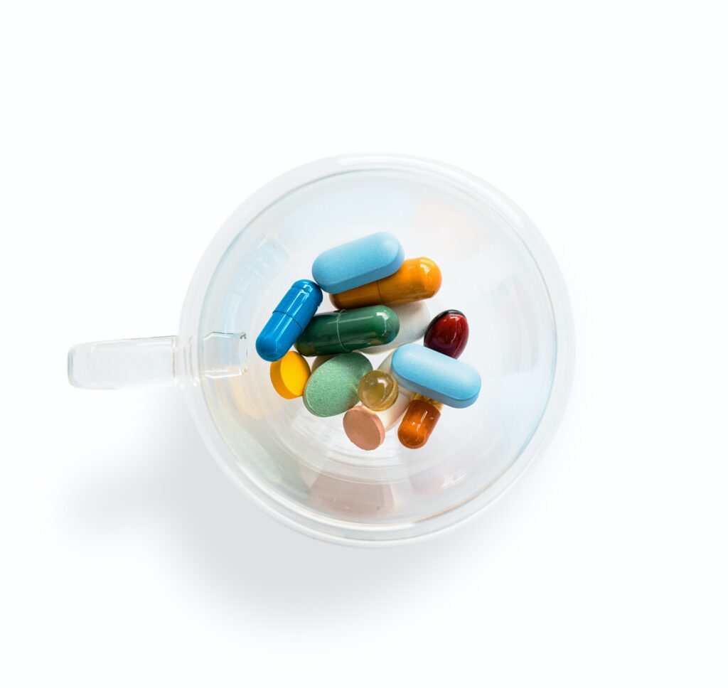 Image of a clear cup with a selection of colourful pills inside it. 