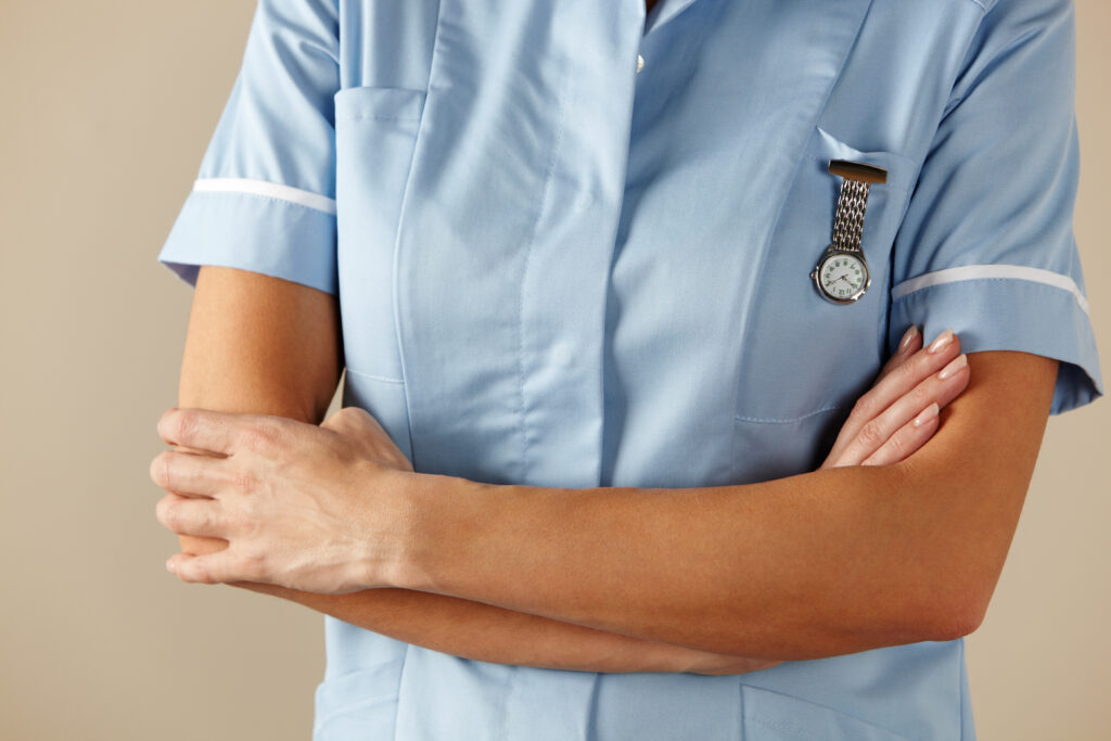 Nurse in uniform seen from the neck down, with arms folded.