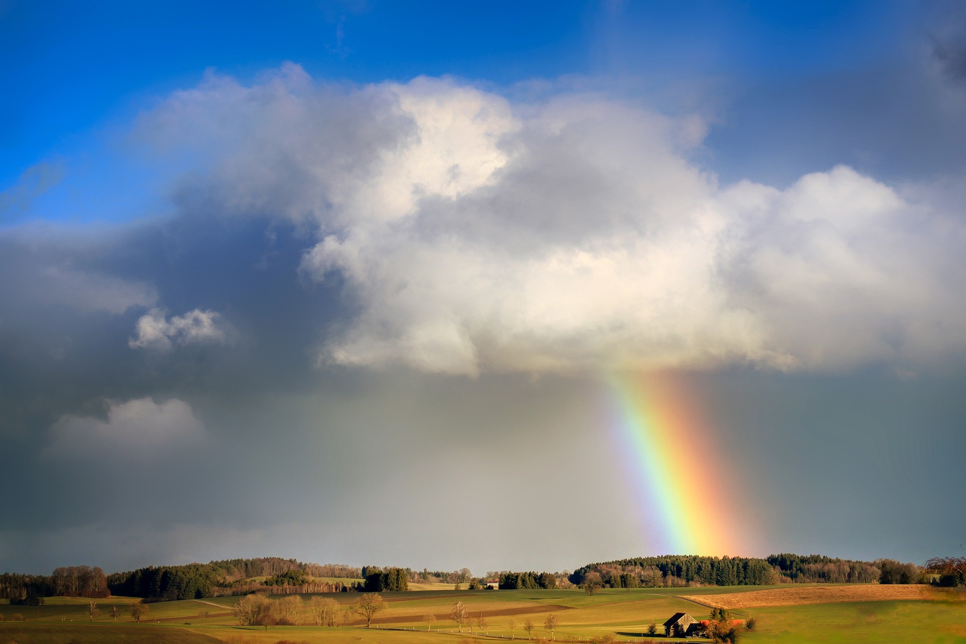 Photo of blue sky, gray clouds and a rainbow.