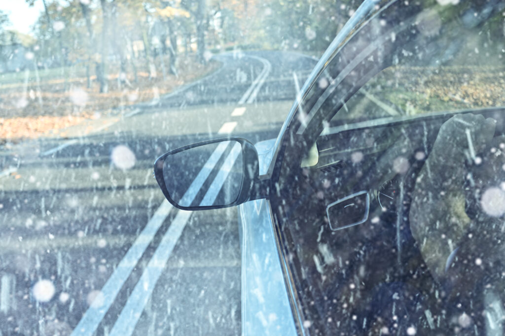 Car window and wing mirror as car is driven through snow