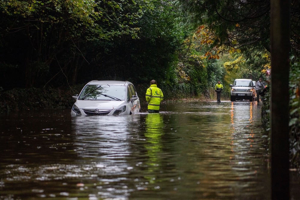 Men retrieving a car that has been abandoned in flood water