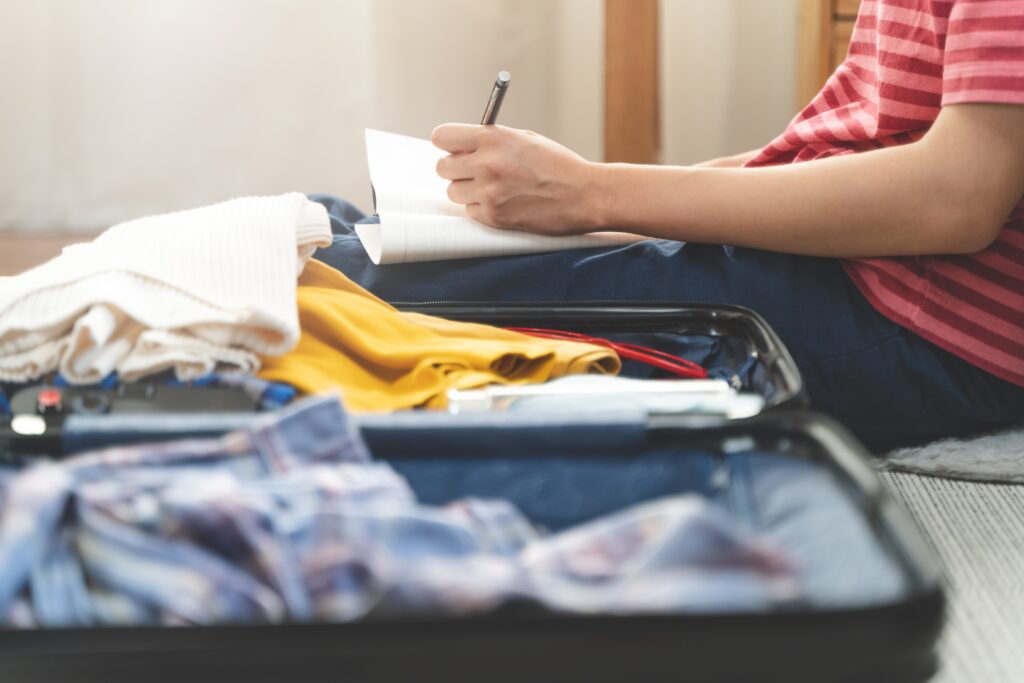 Person making a list as they check a suitcase before travel