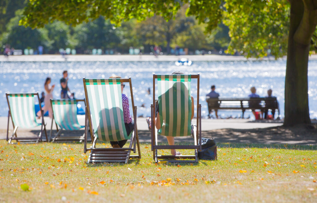 Two deckchairs by a lake in a park