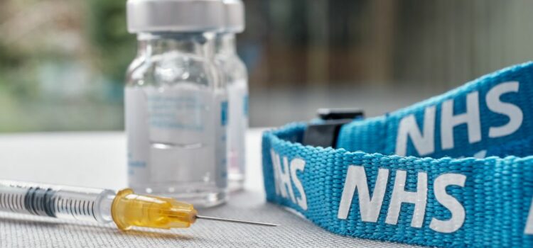 Syringe alongside vials and an NHS lanyard