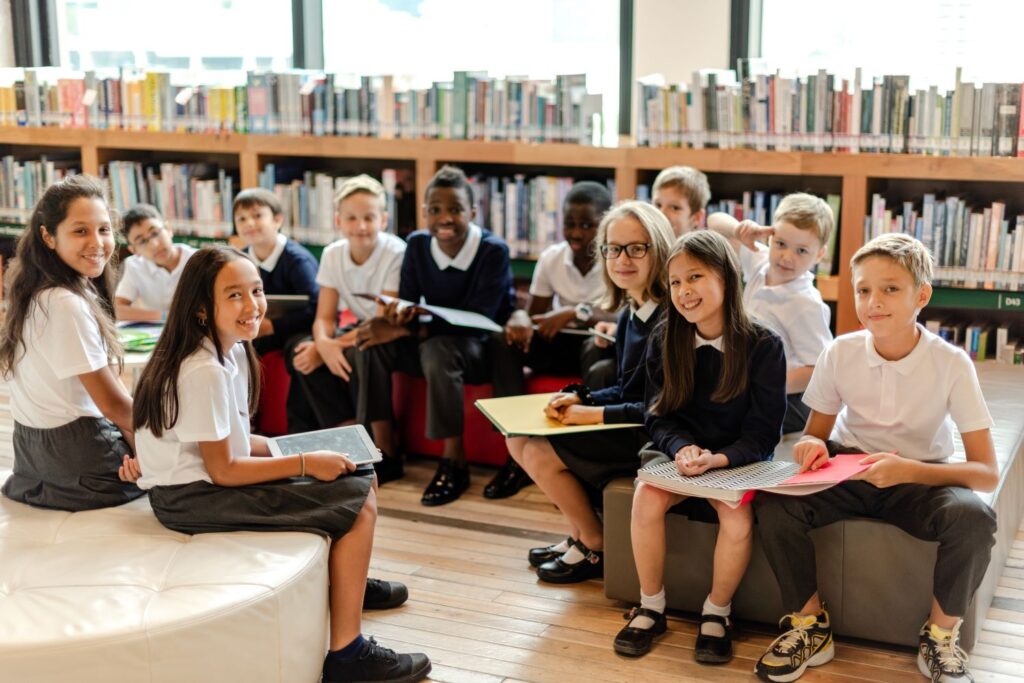 A group of children wearing uniforms sit in a school library