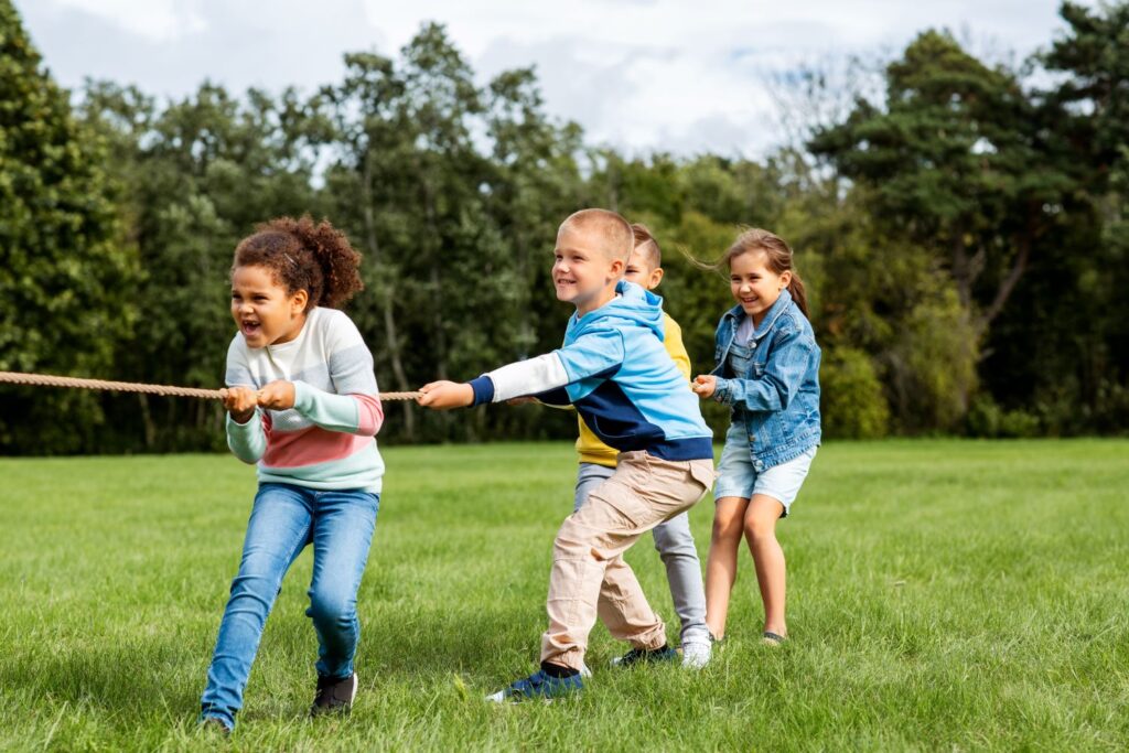 Four children playing tug of war on a sunny day