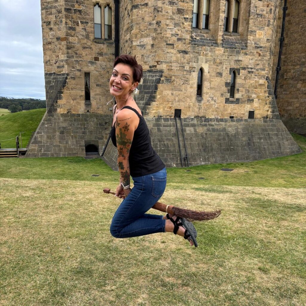 Samara in the grounds of a castle, leaping into the air pretending to ride a wicker broomstick.