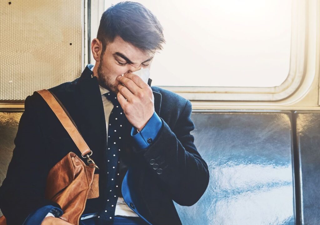Man with a beard blowing his nose on a tissue