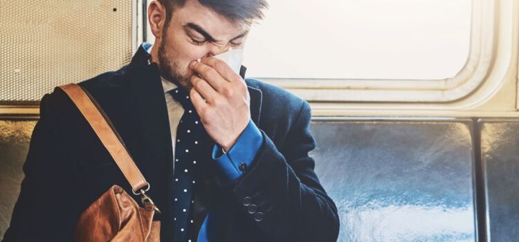 Man with a beard blowing his nose on a tissue