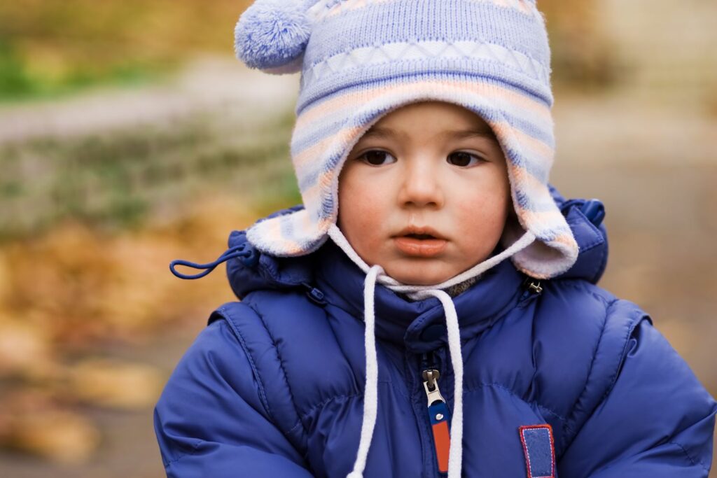 Child wearing woolly hat and padded suit while out in the park