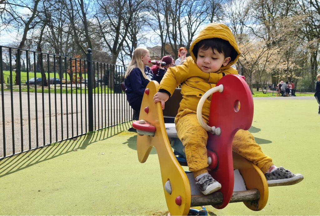 Young child in a yellow suit plays in a playground