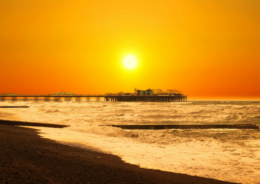 A landscape image of a sunset behind a seaside pier