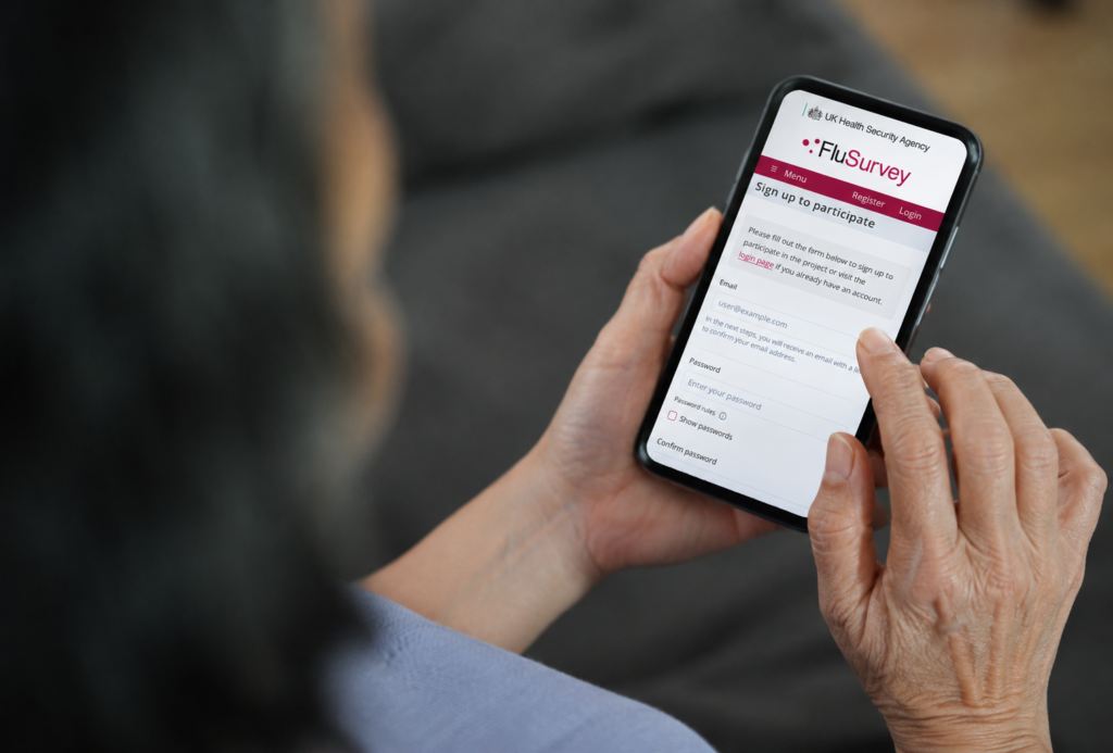 Hands holding a mobile phone, with the FluSurvey registration form on the screen